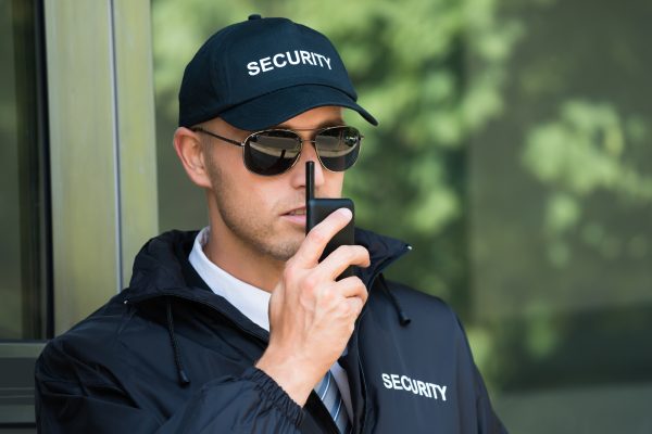Portrait Of Young Security Guard Talking On Walkie-talkie